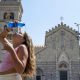 A girl pours a bottle of water on her face and head as she cools off in front of a church in the centre of Messina, on the island of Sicily