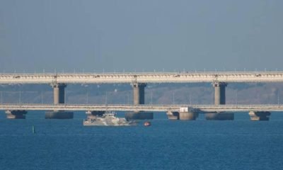 An armed ship sails next to Crimean bridge connecting the Russian mainland with the peninsula across the Kerch Strait, Crimea