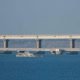 An armed ship sails next to Crimean bridge connecting the Russian mainland with the peninsula across the Kerch Strait, Crimea