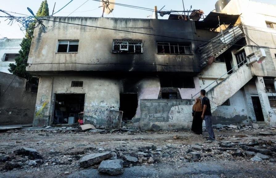 Palestinians look at a damaged building, after the Israeli army's withdrawal from the Jenin camp