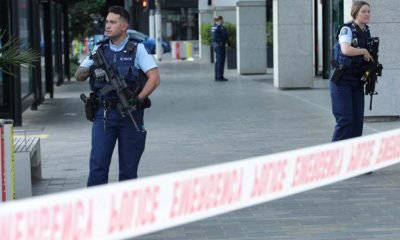 Police officers stand guard near the location of the deadly shooting in Auckland, New Zealand