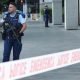 Police officers stand guard near the location of the deadly shooting in Auckland, New Zealand