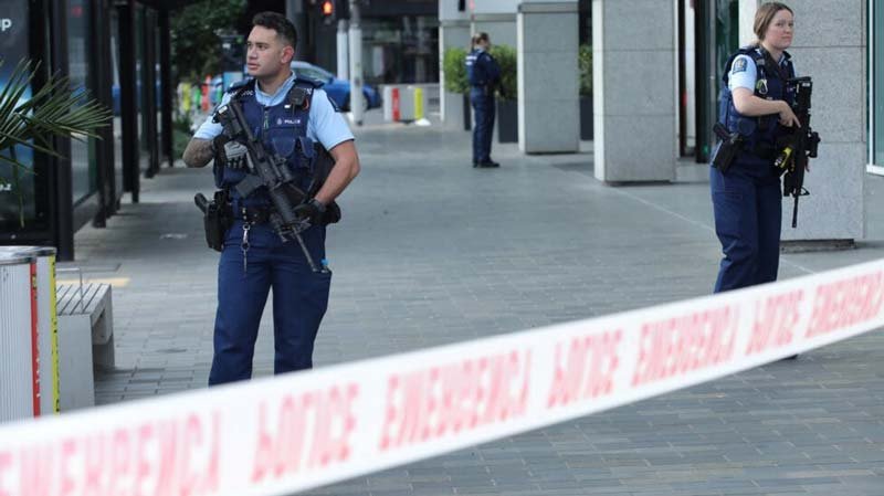 Police officers stand guard near the location of the deadly shooting in Auckland, New Zealand