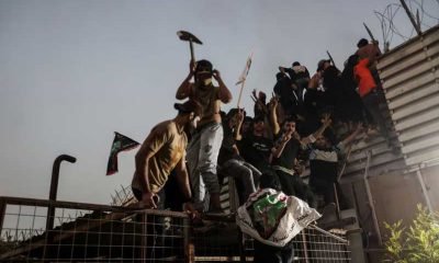 Protesters climb a fence as they gather near the Swedish embassy in Baghdad hours after the embassy was stormed and set on fire ahead of an expected Koran burning in Stockholm, in Baghdad, Iraq, July 20, 2023.