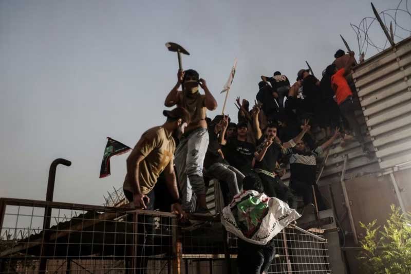 Protesters climb a fence as they gather near the Swedish embassy in Baghdad hours after the embassy was stormed and set on fire ahead of an expected Koran burning in Stockholm, in Baghdad, Iraq, July 20, 2023.