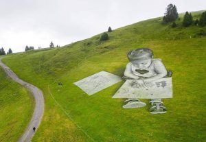 Swiss-French artist SAYPE walks towards his land art painting representing a child drawing at the Col de Bretaye in Villars-sur-Ollon, Switzerland,