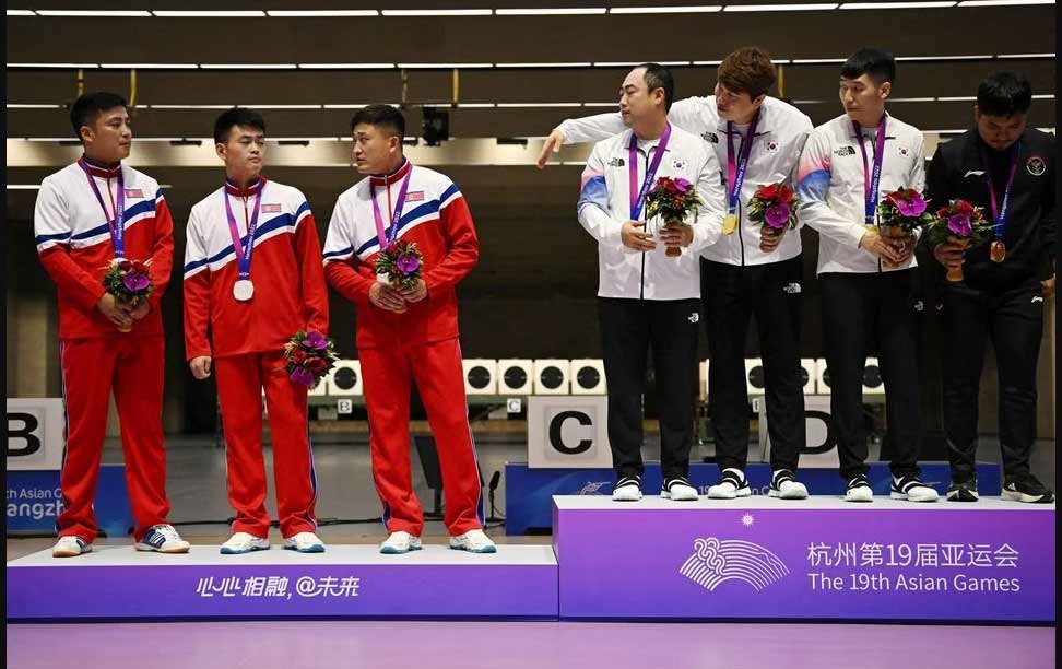 Asian Games - Hangzhou 2022 - Shooting - Fuyang Yinhu Sports Centre, Hangzhou, China - September 25, 2023 Gold medallists South Korea's Ha Kwang-chul, Jeong You-jin and Your Bin Kwak stand on the podium after the Men's Team 10m Running Target Mixed event alongside silver medallists North Korea's Kwon Kwang-il, Pak Myong-won and Songjun Yu