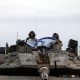 Israeli soldiers hold an Israeli flag while in a tank near Israel's border with the Gaza Strip