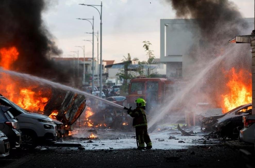 emergency personnel works to extinguish the fire after rockets are launched from the Gaza Strip, as seen from the city of Ashkelon, Israel