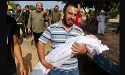 A mourner carries the body of a child, during the funeral of Palestinians from al-Astal family, who were killed in Israeli strikes, in Khan Younis in the southern Gaza Strip, October 22, 2023