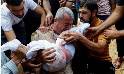 A mourner reacts while burying the body of a Palestinian child of al-Agha family, who was killed in Israeli strikes, in Khan Younis in the southern Gaza Strip