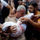 A mourner reacts while burying the body of a Palestinian child of al-Agha family, who was killed in Israeli strikes, in Khan Younis in the southern Gaza Strip