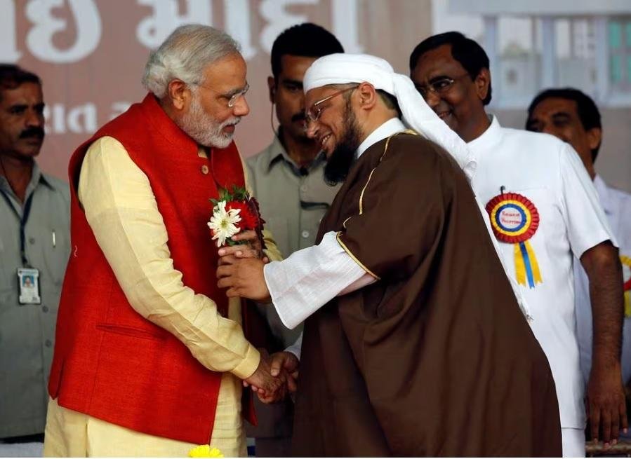 Hindu nationalist Narendra Modi (2nd L), prime ministerial candidate for India's main opposition Bharatiya Janata Party (BJP), receives flowers from a Muslim cleric after the inauguration of a hospital owned by a Muslim trust at Balasinore town, east of the western Indian city of Ahmedabad November 10, 2013.