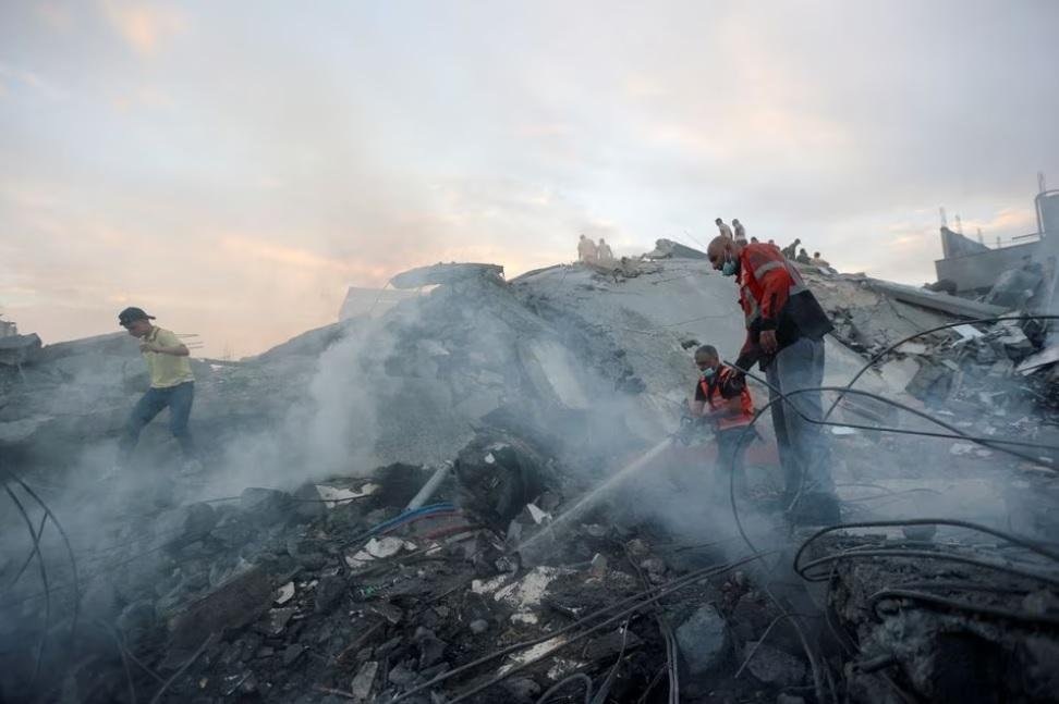 Palestinians conduct search and rescue operations at the site of Israeli strikes on a residential building