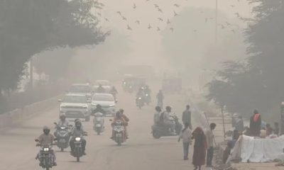 People and vehicles are seen on a road amidst the morning smog in New Delhi, India