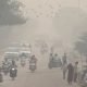 People and vehicles are seen on a road amidst the morning smog in New Delhi, India